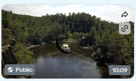 A boat on a river surrounded by lush green forested hills.