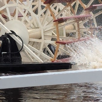 A paddlewheel churning water on a riverboat.