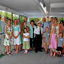 A group of people standing together on a boat with a captain.