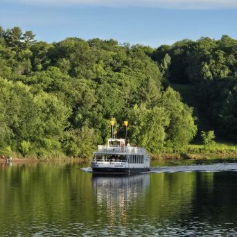 Boat on calm river surrounded by dense green trees.