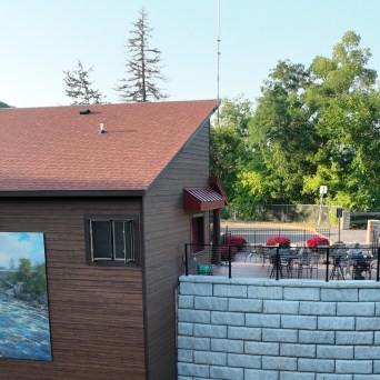 Building with mural and patio overlooking river and bridge.