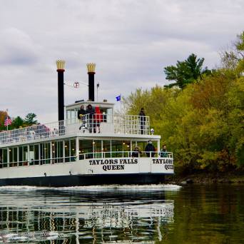 Paddleboat on a river surrounded by autumn trees.
