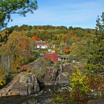 A scenic view of a red building surrounded by autumn trees and rocky terrain.